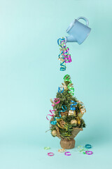 A multicolored streamer flowing from a floating watering can onto a Christmas tree. The minimum...