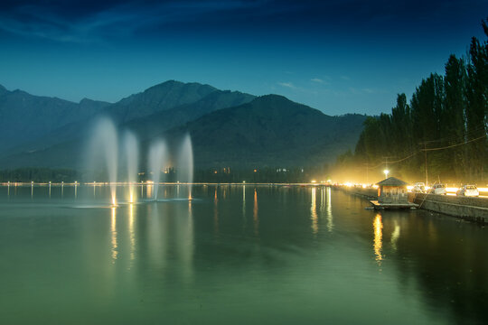 Fountains over the Dal Lake with mountains in the background, at dusk. Dal Lake is the most famous lakes of Jammu and Kashmir, India and is tourist attraction from all over the world.