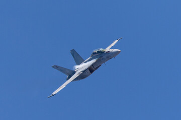 close view of a F-18 Hornet approaching in a high G maneuver, with condensation streaks at the wing roots