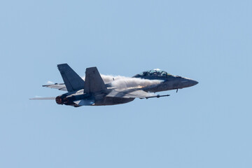 Very close side view of a F-18 Hornet in a high G maneuver, with condensation streaks at the wing roots