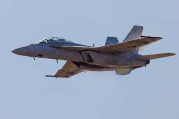 Very close view of a F-18 Hornet approaching in a high G maneuver, with condensation cloud around the plane