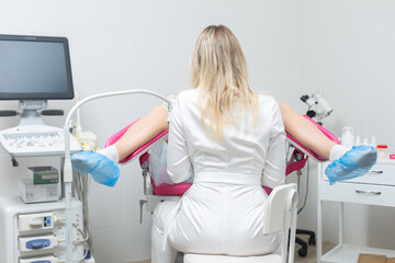 Back view of a gynecologist conducting a routine examination of a girl on a gynecological chair using modern medical technologies - obrazy, fototapety, plakaty