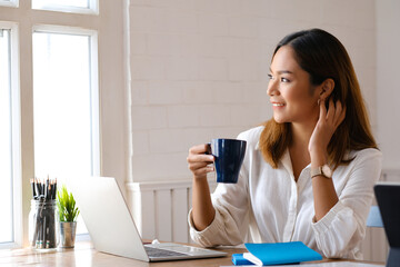 Beautiful woman using laptop at cafe while drinking coffee.