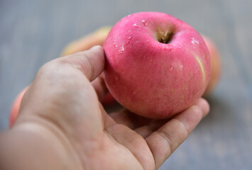 Fuji apples are moderately sized fruits, and have a round to ovate shape with a slightly lopsided appearance. The  skin is smooth, waxy, and has a yellow green base, covered in red pink stripes