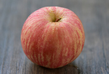 Fuji apples are moderately sized fruits, and have a round to ovate shape with a slightly lopsided appearance. The  skin is smooth, waxy, and has a yellow green base, covered in red pink stripes