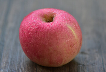 Fuji apples are moderately sized fruits, and have a round to ovate shape with a slightly lopsided appearance. The  skin is smooth, waxy, and has a yellow green base, covered in red pink stripes
