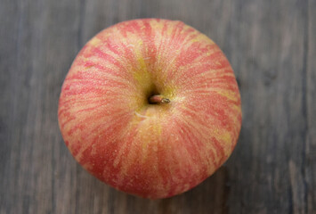 Fuji apples are moderately sized fruits, and have a round to ovate shape with a slightly lopsided appearance. The  skin is smooth, waxy, and has a yellow green base, covered in red pink stripes