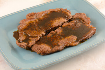 New York strip steak with garlic brown sauce on blue serving plate