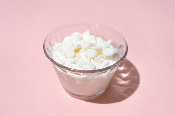Cottage cheese in a glass container on a pink background