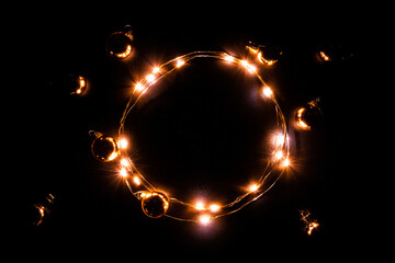 Christmas lights border. Golden light garland decoration, gold bulb isolated on black for xmas party ornament decor background. Glowing lights for Christmas Holiday.