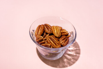 Walnuts in a glass bowl on pink background