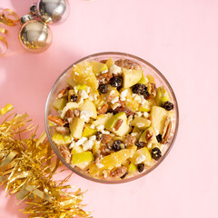 Apple salad with walnuts for Christmas on a pink background
