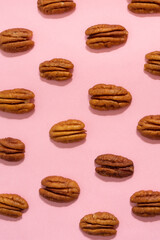 Walnuts creating a pattern on a pink background