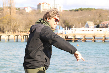a curly-haired man walks by the sea on an autumn day