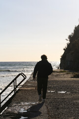 Fototapeta premium a curly-haired man walks by the sea on an autumn day