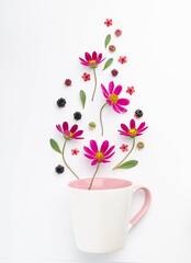 Composition of berries and flowers over a cup.
