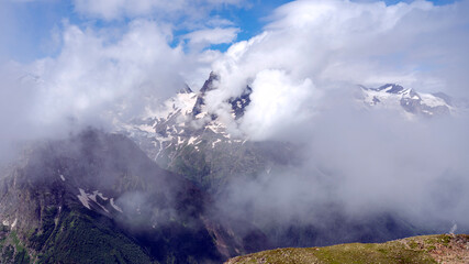 Photo Summer Mountains Caucasus in the clouds. Beautiful snow-capped mountains.