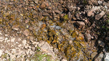 A small stream formed by melting snow in summer on the mountain. North Caucasus.