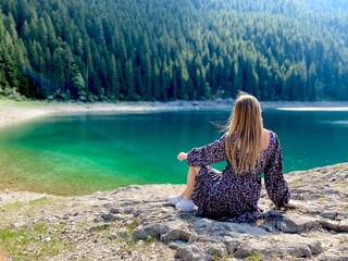 Unusual natural picturesque place. Beautiful lake and a girl sitting on the rock, concept of solitude, calmness.