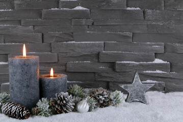 Kerzen mit Weihnachtsschmuck im Schnee.
