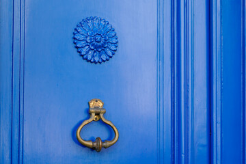Old iron ring on vintage blue retro door for knocking on facade classic house