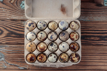Top view of Quail eggs in cardboard box on wooden background
