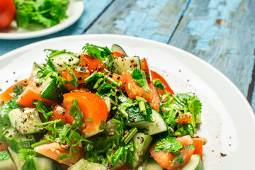 Mediterranean salad with tomatoes, cucumber, coriander, onions, olive oil and lemon in a white ceramic plate. Healthy vegetarian food, oriental and Mediterranean cuisine. Top view. Copy space. No.01