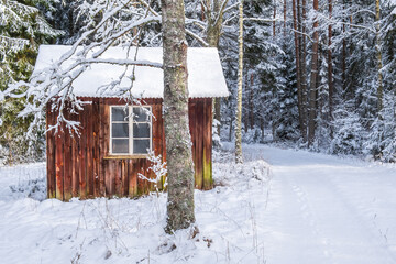 Red cottage in by a road with footprints in the snow