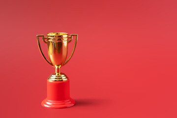 Gold color victory cup on red background