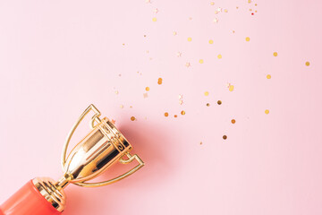 Stars fly out of the gold colored victory cup on pink background