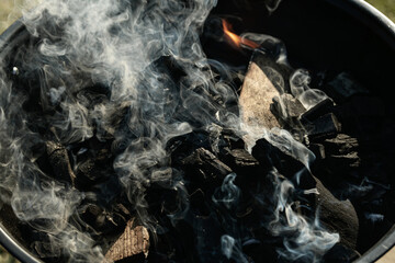 Preparing the barbecue and setting on the fire. Charcoal is lit and smoke is getting out from it before starting to cook.
