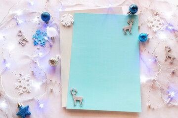 blank sheet for Christmas wishes, shopping list on the background of Christmas tree glowing garland and Christmas tree decorations