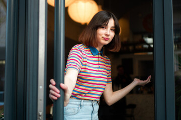A cute waitress is at the entrance door, inviting you to come to the bar.