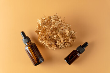 A mock-up of a blank glass bottles with face and eyedropper lies on a beige background. Skin care serum template. The concept of a natural cosmetic product, cosmetics with oil. Copyspace