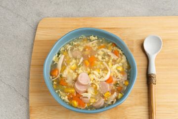 Corn cream soup with chicken, sausage, egg, carrots and cornstarch, savory and delicious. Served in bowl, copy space.

