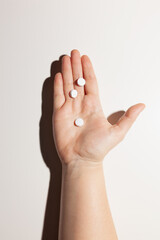 Three white pills on outstretched male palm on white background