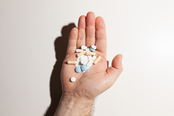 Colorful pills on outstretched male palm on white background