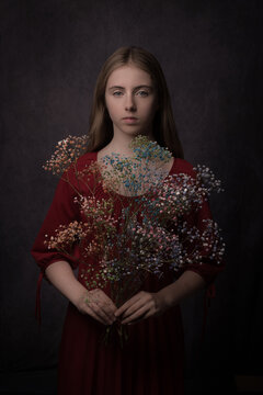 Fine art studio portrait of a woman in red dress holding colorful flowers