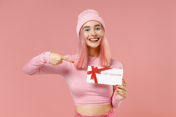 Young woman 20s with bright dyed rose hair in rosy top shirt hat hold point on gift certificate coupon voucher card for store isolated on plain light pastel pink background. People lifestyle concept.