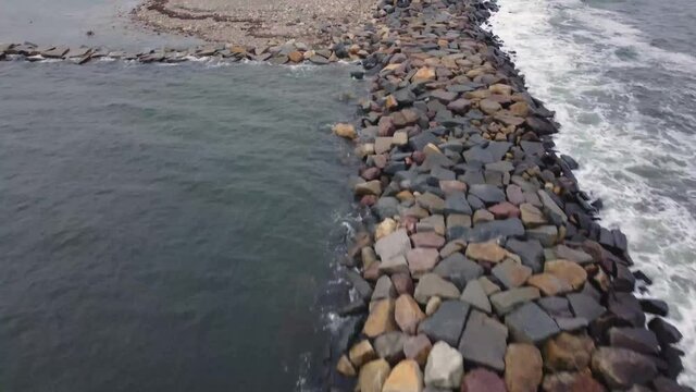 Breakwater reveal shot of a lighthouse seaside of the coast shore in Scituate