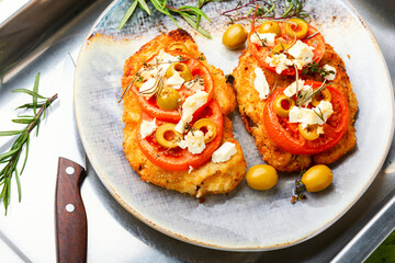 Fried schnitzel with olives and tomato