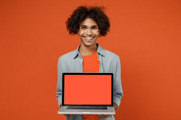 Young student black man 50s wearing blue shirt t-shirt hold use work on laptop pc computer browsing with blank screen workspace area isolated on plain orange color background People lifestyle concept