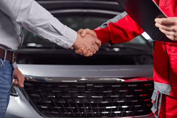 Anonymous mechanic and customer shaking hand after finishing car diagnosis