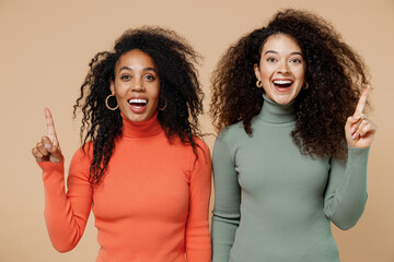 Two insighted smart proactive young curly black women friends 20s wearing casual shirts clothes holding index finger up with great new idea isolated on plain pastel beige background studio portrait.