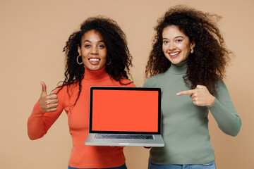 Two young curly black women friends 20s wear casual shirts clothes hold use work on laptop pc...