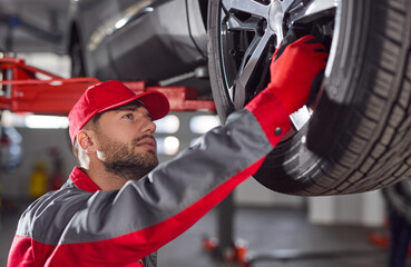 Mechanic repairing car wheel in garage
