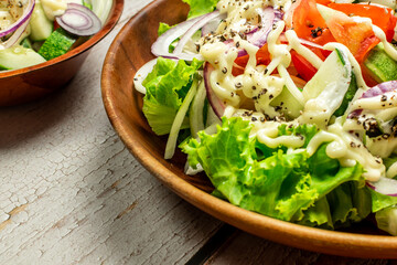Homemade salad with dressing,cucumber, tomatoes,lettuce,shallot and cream cheese.  Rustic style. Selective Focus. Top view. Copy space. No.03