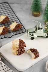 Several coconut flakes cookies dipped in chocolate on a white marble board and baking rack, christmas decoration