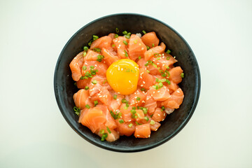 Salmon with egg rice in a black bowl on a white background