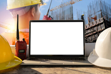 White and yellow safety helmet, laptops placed on a table in the construction area. Engineers are in control use communication tools